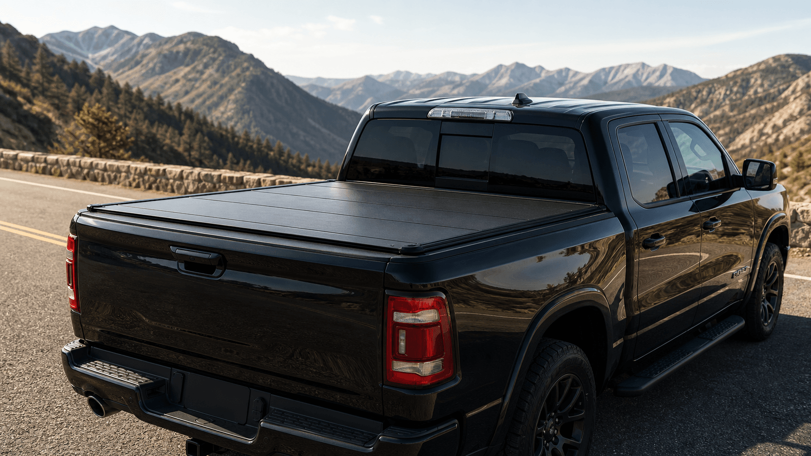 Black pickup truck with a closed hard tonneau cover on a mountain road